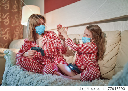Woman and young girl wearing pajamas and medical protective mask Woman and young girl wearing pajamas and medical protective mask 77057590
