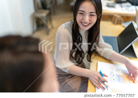 Two women having a meeting while looking at the floor plan of the house Two women having a meeting while looking at the floor plan of the house 77057707