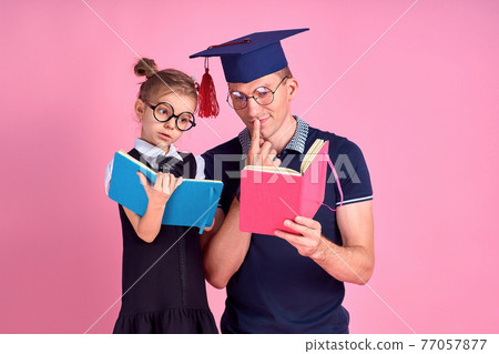 Man in academic hat holding book, study together with cute prete Man in academic hat holding book, study together with cute prete 77057877