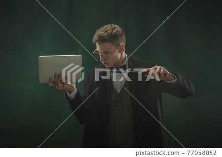 Young man in art action isolated on dark green background. Retro style, comparison of eras concept. Young man in art action isolated on dark green background. Retro style, comparison of eras concept. 77058052