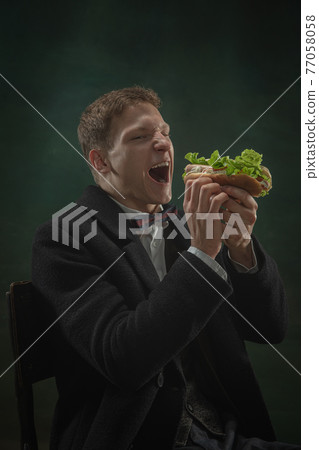 Young man in art action isolated on dark green background. Retro style, comparison of eras concept. Young man in art action isolated on dark green background. Retro style, comparison of eras concept. 77058058