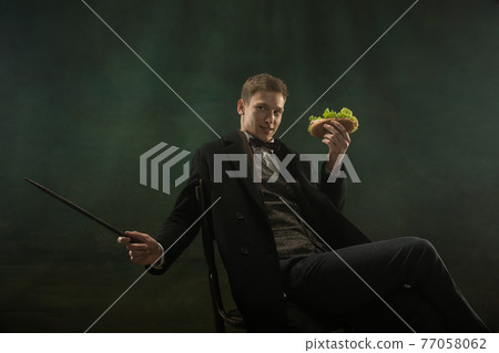 Young man in art action isolated on dark green background. Retro style, comparison of eras concept. 77058062