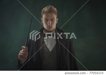 Young man in art action isolated on dark green background. Retro style, comparison of eras concept. 77058153