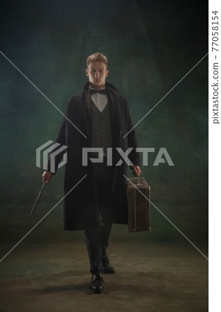 Young man in art action isolated on dark green background. Retro style, comparison of eras concept. 77058154