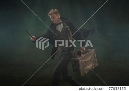 Young man in art action isolated on dark green background. Retro style, comparison of eras concept. 77058155