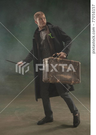 Young man in art action isolated on dark green background. Retro style, comparison of eras concept. Young man in art action isolated on dark green background. Retro style, comparison of eras concept. 77058157