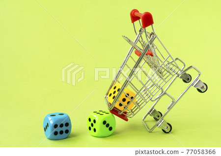 Shopping cart with colorful dice on green background Shopping cart with colorful dice on green background 77058366