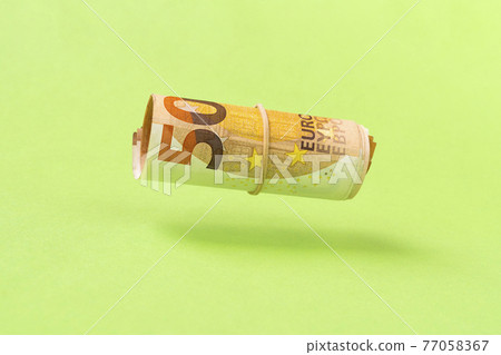 Roll of euro currency levitating over green background Roll of euro currency levitating over green background 77058367