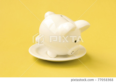 White plate with piggy bank on yellow background White plate with piggy bank on yellow background 77058368