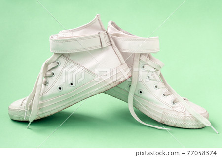 Pair of white shoes on the blue background Pair of white shoes on the blue background 77058374