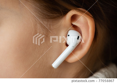 Wireless earphone in the girl's ear. 77058867