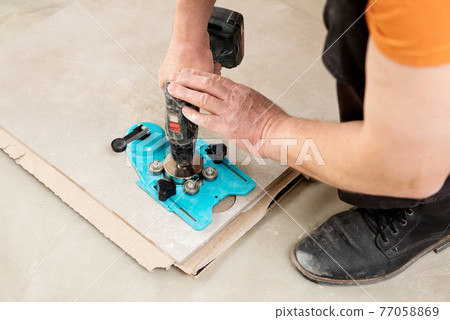 A tiler uses a caliper with a suction cup to drill holes in the ceramic tile. A tiler uses a caliper with a suction cup to drill holes in the ceramic tile. 77058869