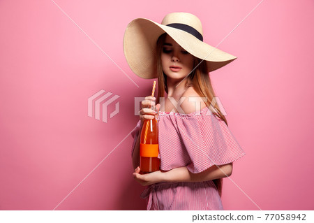 Photo of charming woman wearing straw hat drinking juice from glass bottle isolated over pink background.  77058942