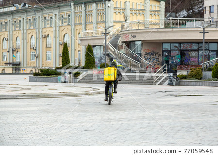 Kyiv, Ukraine - March, 22, 2020: Glovo delivery service courier on an empty Postal Square in Kiev. Kyiv, Ukraine - March, 22, 2020: Glovo delivery service courier on an empty Postal Square in Kiev. 77059548
