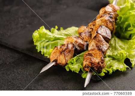 Two portions of shish kebab on a stone plate with salad. Two portions of shish kebab on a stone plate with salad. 77060389