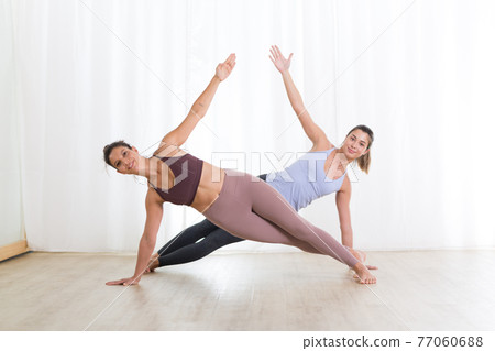Portrait of active sporty young women practicing yoga in studio. Healthy active lifestyle, working out indoors in gym 77060688