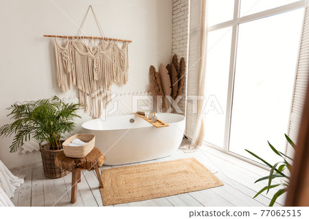 Cozy modern minimalistic bathroom interior with big white bathtube indoors Cozy modern minimalistic bathroom interior with big white bathtube indoors 77062515