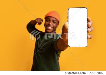 Cheerful Black Guy Pointing On Smartphone With White Screen In His Hands 77062802