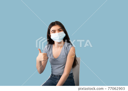 Vaccinated teen girl in face mask showing plaster bandage on her arm after getting covid-19 vaccine injection Vaccinated teen girl in face mask showing plaster bandage on her arm after getting covid-19 vaccine injection 77062903