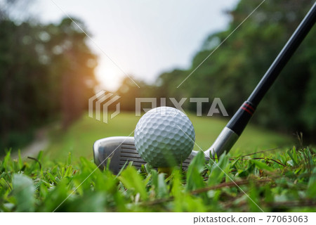 Golf balls and golf clubs on a green lawn in a beautiful golf course with morning sunshine. Golf balls and golf clubs on a green lawn in a beautiful golf course with morning sunshine. 77063063