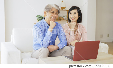 Middle-aged couple thinking while using a computer 77063206