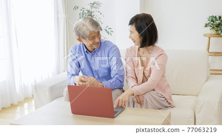 Middle-aged couple using a computer in the living room 77063219