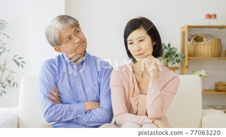 Middle-aged couple thinking in the living room 77063220