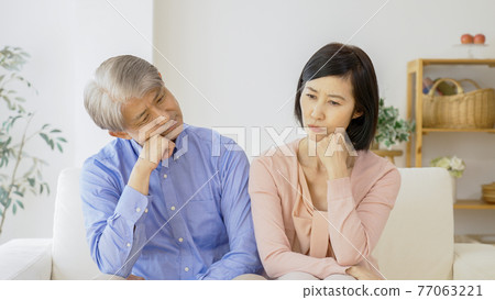 Middle-aged couple thinking in the living room 77063221
