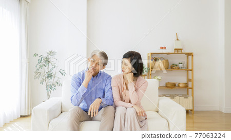 Middle-aged couple thinking in the living room Middle-aged couple thinking in the living room 77063224