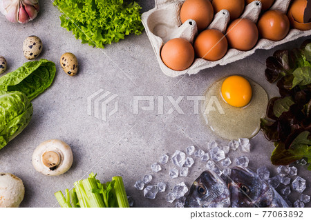 Frame of raw cooking ingredients for tasty and healthy food. Fresh dorado fish on ice, vegetables, eggs on gray concrete background top view. 77063892