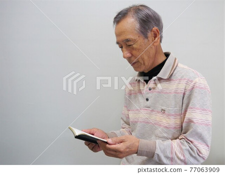Senior man looking at a notebook 77063909