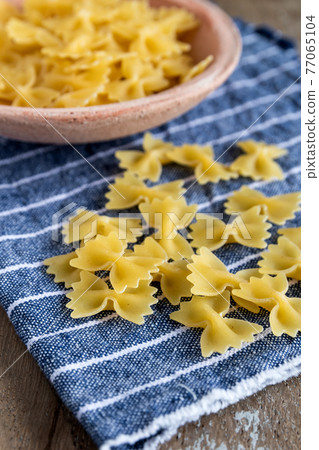 uncooked mini farfalle pasta on rustic background 77065104