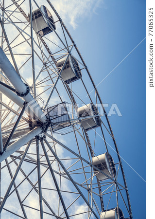 Gray or white metal ferris wheel with closed passenger cabins close-up in the amusement park 77065325