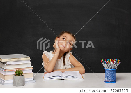 happy schoolgirl sitting at table in the classroom happy schoolgirl sitting at table in the classroom 77065505