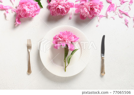 Festive table setting with pink peony flowers on a white table. View from above. Festive table setting with pink peony flowers on a white table. View from above. 77065506