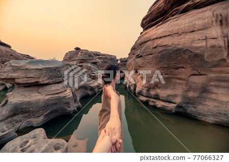 Beautiful asian woman holding hands with couple in rock gorge of grand canyon at evening 77066327