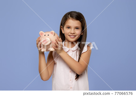 smiling child girl holding pink piggy bank 77066576