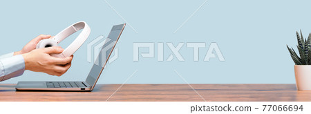 Laptop and hands with headphones on white desk 77066694
