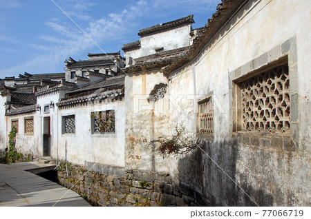 Xidi Ancient Town in Anhui Province, China. A quiet street in the old town of Xidi called the Back Rivulet. This path follows a small stream past local houses. Traditional architecture in Xidi, China. 77066719