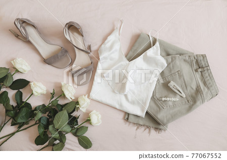 Jeans, sandals and bouquet of flowers on beige background. Top view of female casual spring summer outfit. Trendy stylish women clothes. Flat lay Jeans, sandals and bouquet of flowers on beige background. Top view of female casual spring summer outfit. Trendy stylish women clothes. Flat lay 77067552