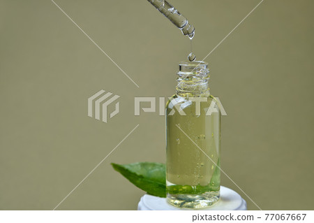 drop of citrus oil close-up macro drips from a pipette into a bottle 77067667