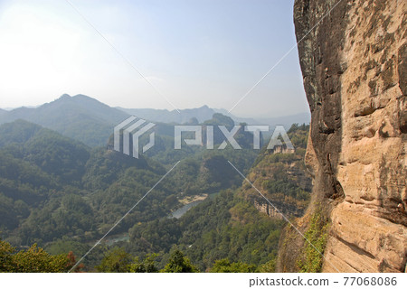 Wuyishan mountains in Fujian Province, China. On the path to DaWang (Great King) Peak. View over the mountains with Nine Bends River or Nine Twists Stream below. Wuyishan is a UNESCO site in China. 77068086