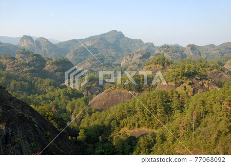 Wuyishan mountains in Fujian Province, China. Scenic view over the peaks of Wuyi mountains. A classic view of the hills from Roaring Tiger Rock. Wuyishan is a UNESCO World Heritage site in China. 77068092