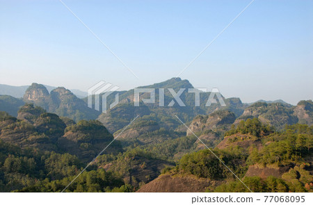 Wuyishan mountains in Fujian Province, China. Scenic view over the peaks of Wuyi mountains. A classic view of the hills from Roaring Tiger Rock. Wuyishan is a UNESCO World Heritage site in China. 77068095
