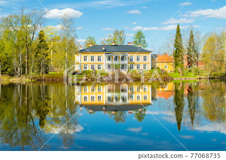 Kouvola, Finland - May 16, 2019: Beautiful wooden Rabbelugn Manor - Takamaan Kartano. Wrede family house was built in 1820 on the river Kymijoki bank. Kouvola, Finland - May 16, 2019: Beautiful wooden Rabbelugn Manor - Takamaan Kartano. Wrede family house was built in 1820 on the river Kymijoki bank. 77068735