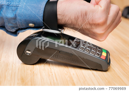 Customer paying through smartwatch using NFC technology. Contactless payment terminal machine. Customer paying through smartwatch using NFC technology. Contactless payment terminal machine. 77069989