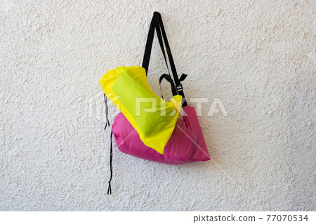 Pink and yellow sports bags with a black belt on a white rough background Pink and yellow sports bags with a black belt on a white rough background 77070534