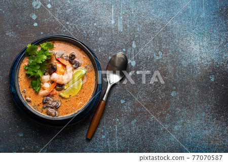 Thai soup Tom Yum with seafood in bowl from above copy space Thai soup Tom Yum with seafood in bowl from above copy space 77070587