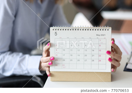 Female hands with pink manicure holding looseleaf paper calendar closeup Female hands with pink manicure holding looseleaf paper calendar closeup 77070653
