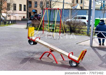 Swing against the background of the playground in the courtyard of condominium Swing against the background of the playground in the courtyard of condominium 77071482